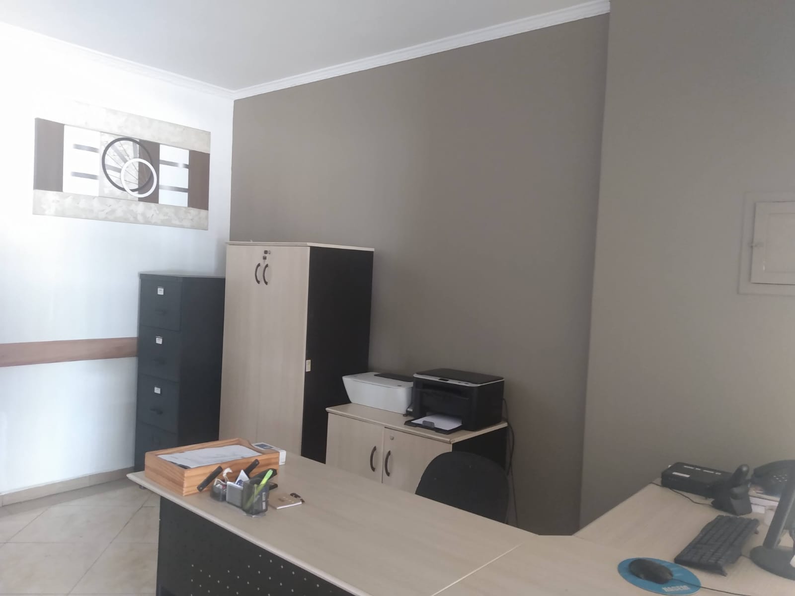 Recepção de escritório reformada, com pintura em tom neutro e moldura de gesso